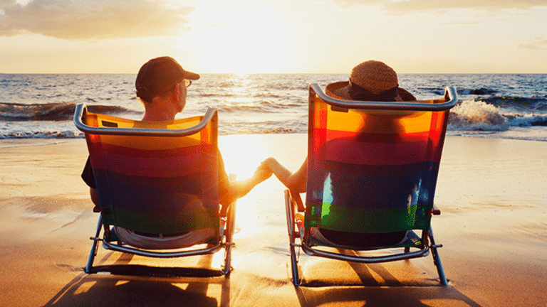Two older people sitting on beach chairs watching the sunset